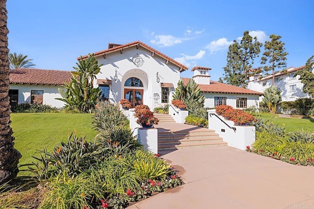 mediterranean / spanish home with french doors and a front lawn