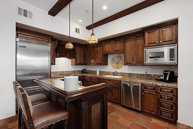 kitchen featuring sink, hanging light fixtures, a center island, built in appliances, and custom exhaust hood