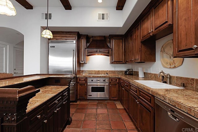 kitchen featuring dark brown cabinetry, stainless steel appliances, sink, and custom range hood