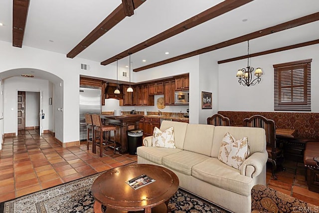 tiled living room with beam ceiling, sink, and a notable chandelier