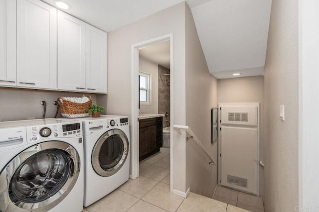 clothes washing area featuring cabinets, light tile patterned floors, and washing machine and clothes dryer