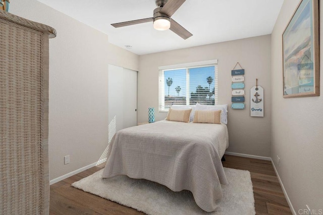 bedroom featuring dark wood-type flooring, a closet, and ceiling fan