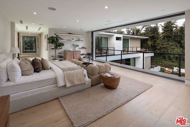 bedroom with a wall of windows, light hardwood / wood-style floors, access to outside, and multiple windows