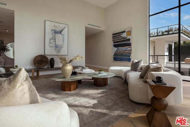 living room with wood-type flooring and a towering ceiling