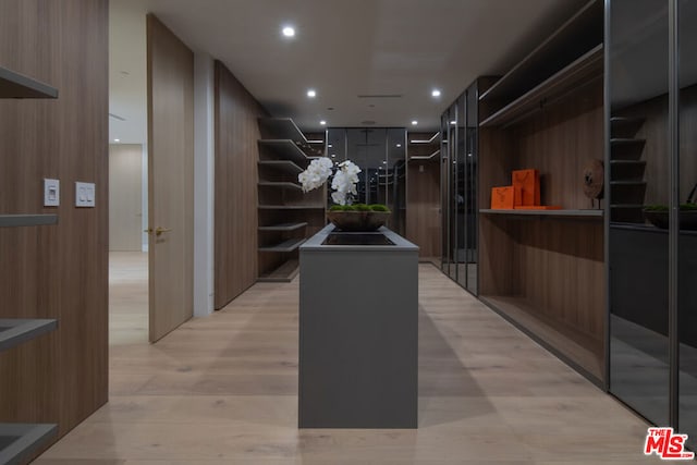 hall with light hardwood / wood-style flooring and wood walls