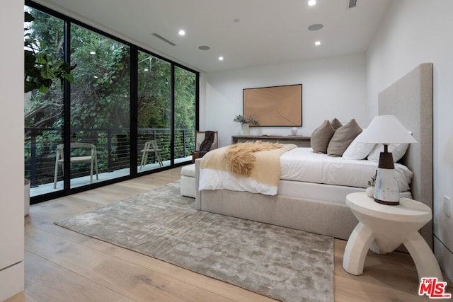 bedroom with access to exterior, light hardwood / wood-style flooring, and expansive windows