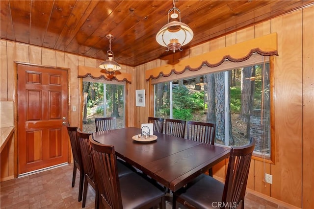 dining room featuring wooden ceiling and wooden walls