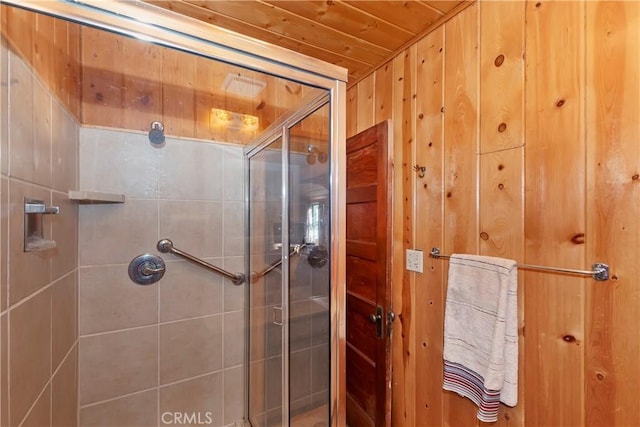 bathroom featuring a shower with door, wood ceiling, and wood walls