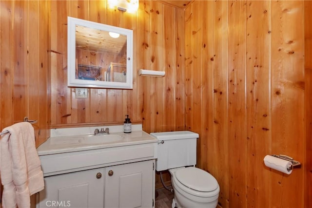 bathroom featuring vanity, toilet, and wood walls