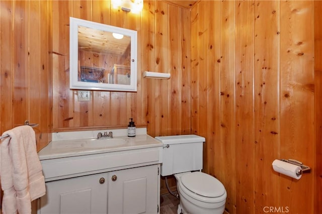 bathroom featuring vanity, wood walls, and toilet