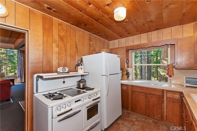 kitchen featuring wood ceiling, white appliances, a wealth of natural light, and wood walls