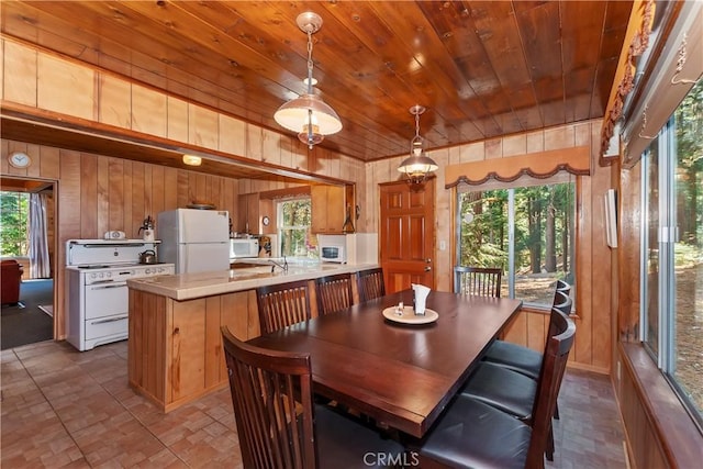 dining room with sink, wood ceiling, and wooden walls