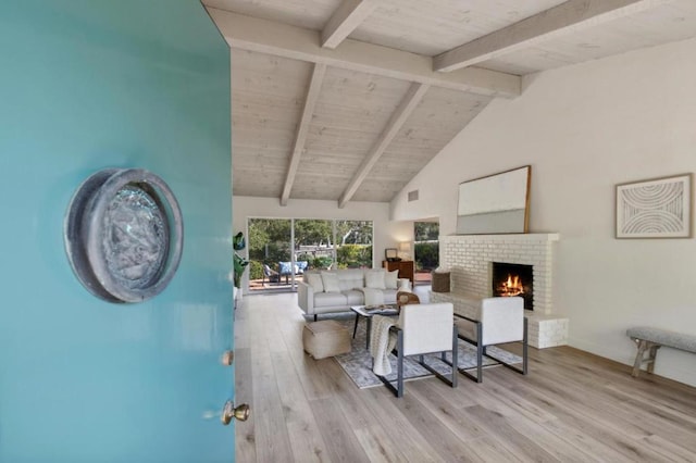 living room with high vaulted ceiling, a fireplace, wood ceiling, light hardwood / wood-style floors, and beam ceiling