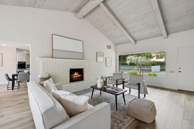 living room featuring beam ceiling, a fireplace, and light wood-type flooring