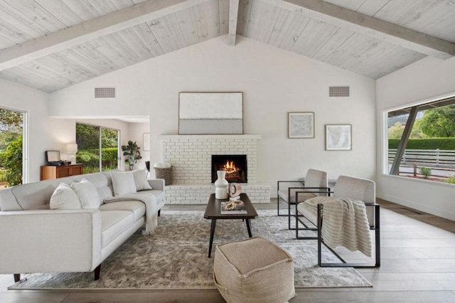 living room with lofted ceiling with beams, a brick fireplace, and light hardwood / wood-style floors