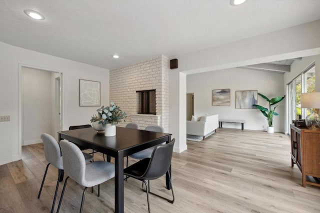 dining area featuring light wood-type flooring and a fireplace