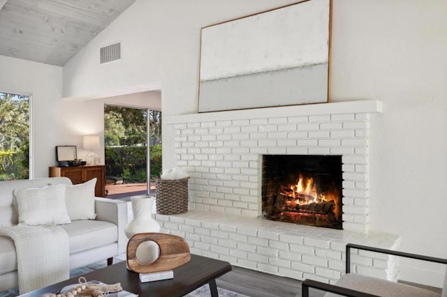 living room with wood ceiling, a brick fireplace, hardwood / wood-style flooring, and vaulted ceiling