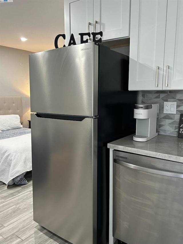 kitchen featuring stainless steel refrigerator, decorative backsplash, white cabinetry, and light wood-type flooring