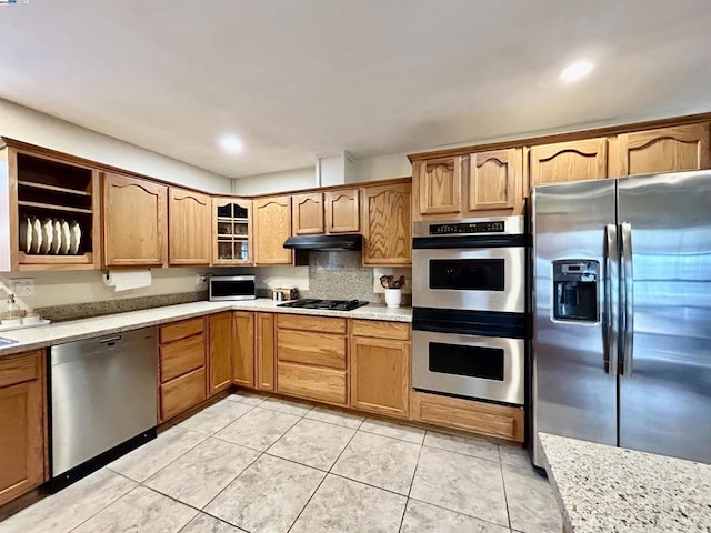 kitchen with light stone counters, light tile patterned floors, and appliances with stainless steel finishes