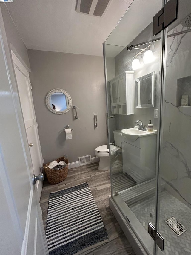 bathroom featuring vanity, hardwood / wood-style flooring, toilet, and walk in shower