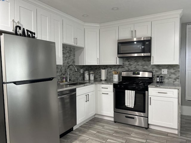 kitchen with decorative backsplash, light stone countertops, stainless steel appliances, sink, and white cabinetry