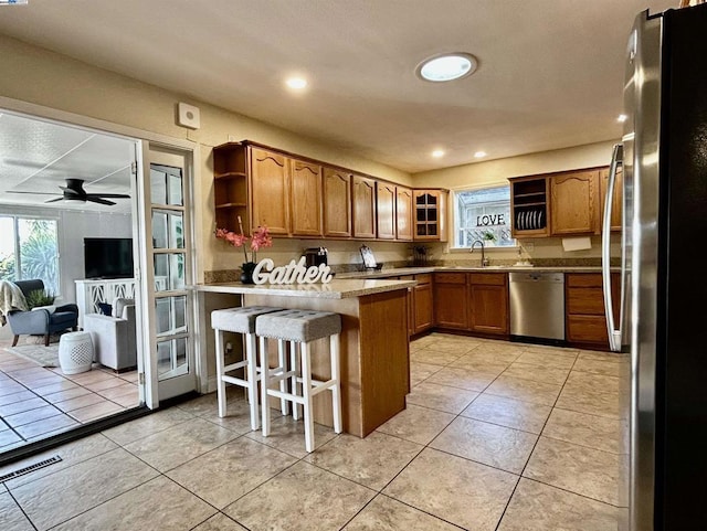 kitchen with kitchen peninsula, a breakfast bar, stainless steel appliances, ceiling fan, and sink