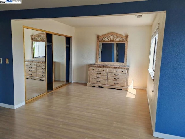 unfurnished bedroom with hardwood / wood-style floors, a closet, and multiple windows