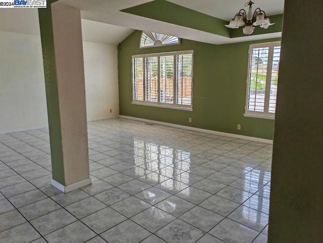 tiled spare room featuring a chandelier and lofted ceiling