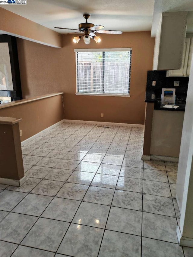 unfurnished dining area with ceiling fan and light tile patterned floors