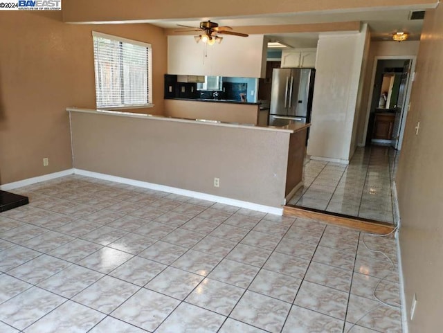 kitchen featuring stainless steel refrigerator, ceiling fan, kitchen peninsula, and light tile patterned floors