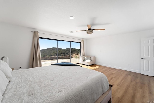 bedroom with a mountain view, ceiling fan, and light hardwood / wood-style flooring