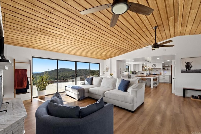 living room with a mountain view, hardwood / wood-style floors, vaulted ceiling, a fireplace, and wood ceiling