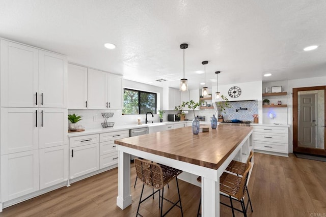 kitchen featuring white cabinets, backsplash, decorative light fixtures, and light hardwood / wood-style floors