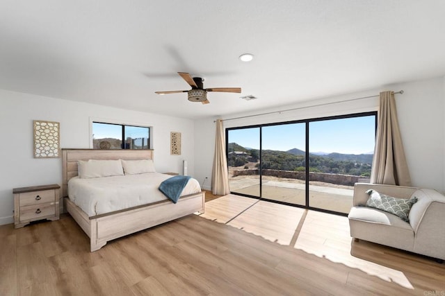 bedroom with access to exterior, ceiling fan, a mountain view, light hardwood / wood-style floors, and multiple windows