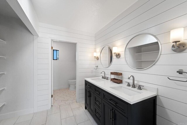 bathroom with tile patterned floors, vanity, toilet, and wooden walls