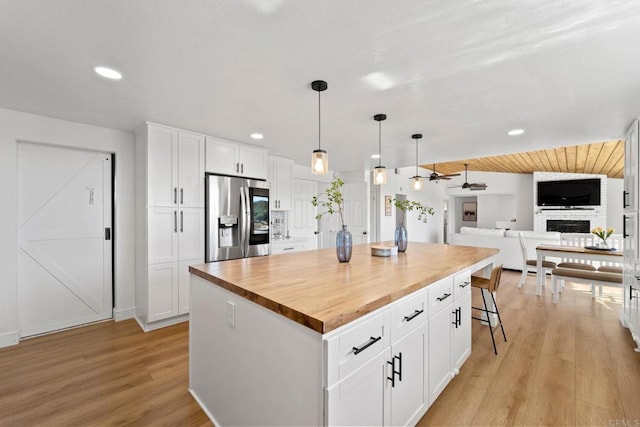 kitchen with a center island, light wood-type flooring, white cabinetry, and stainless steel refrigerator with ice dispenser