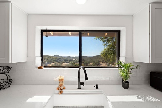 room details featuring a mountain view, white cabinetry, and decorative backsplash