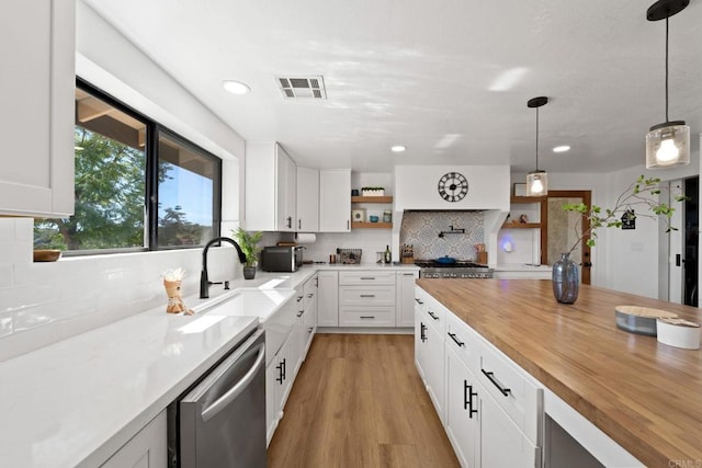 kitchen featuring decorative light fixtures, light hardwood / wood-style floors, dishwasher, and white cabinetry