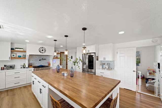 kitchen featuring white cabinets, wood-type flooring, stainless steel appliances, and hanging light fixtures