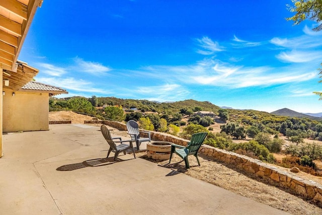 view of patio / terrace with a mountain view and a fire pit