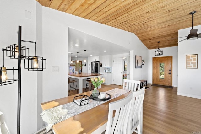 dining room with hardwood / wood-style floors, ceiling fan with notable chandelier, vaulted ceiling, and wooden ceiling