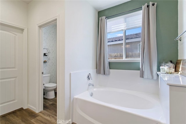 bathroom featuring a tub to relax in, hardwood / wood-style flooring, and toilet