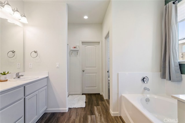 bathroom with vanity, hardwood / wood-style flooring, and a tub