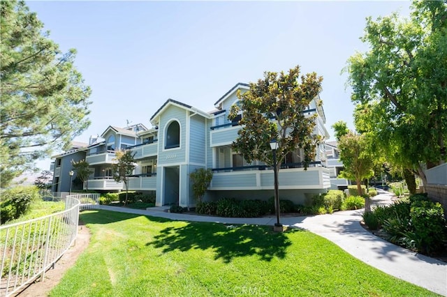 view of front of house featuring a balcony and a front lawn