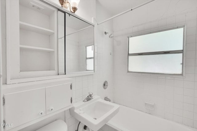 full bathroom with tile walls, sink, tiled shower / bath combo, and toilet