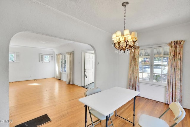 dining space featuring hardwood / wood-style floors, a textured ceiling, and an inviting chandelier