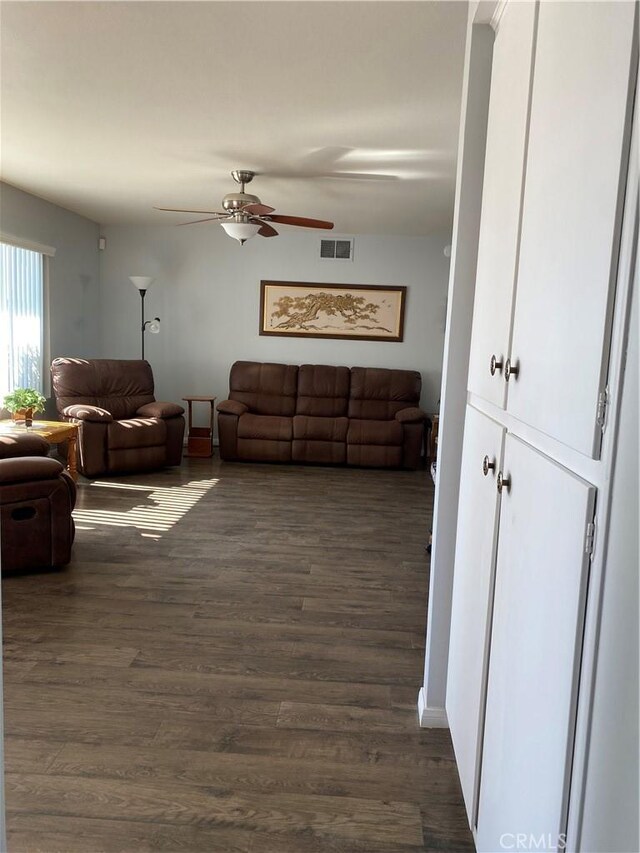 living room featuring ceiling fan and dark wood-type flooring