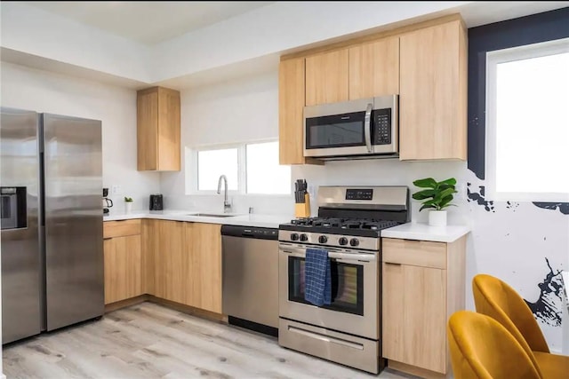 kitchen featuring light brown cabinets, light wood-type flooring, stainless steel appliances, and sink