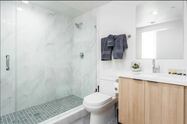 bathroom featuring vanity, a shower with shower door, and toilet