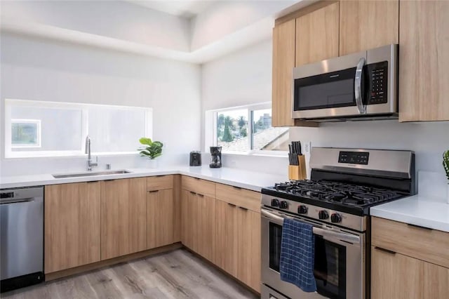 kitchen featuring appliances with stainless steel finishes, light hardwood / wood-style flooring, light brown cabinetry, and sink